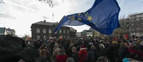 O mulțime de oameni protestează cu steagul Uniunii Europene.