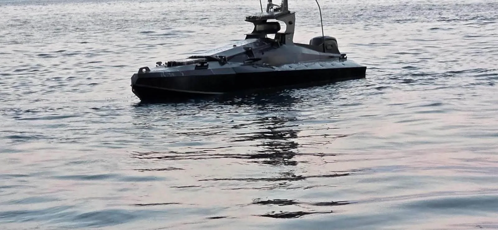 Dronă marină cu explozibil pe apă, reflectată în marea calmă.