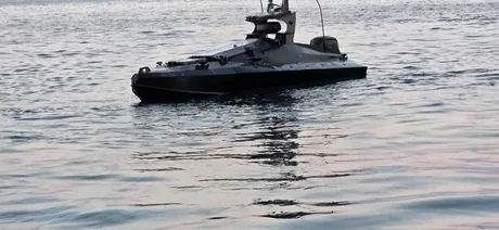 Dronă marină cu explozibil pe apă, reflectată în marea calmă.