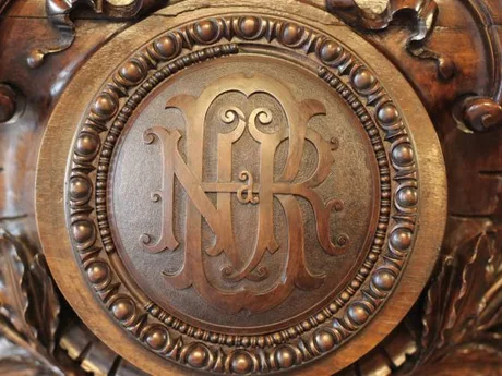 Sigla BNR gravată pe un fundal din lemn sculptat.