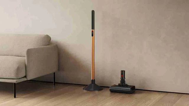 Aspirator Dyson PencilWash lângă o canapea pe un podea din lemn.