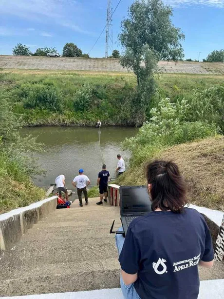 Persoane care monitorizează nivelul apei într-un canal afectat de secetă.