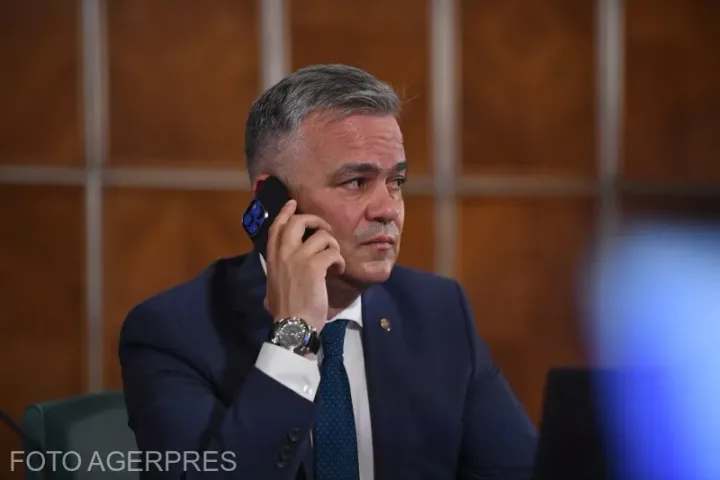 Adrian Veștea discutând la telefon, în birou, cu un aspect concentrat.