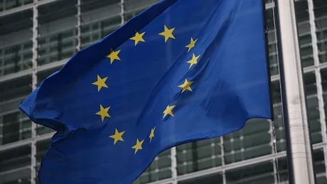 Steagul Uniunii Europene fluturând în fața clădirii instituțiilor europene.
