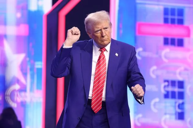 Donald Trump dansează la un miting, purtând un costum al brandului Jos. A. Bank.