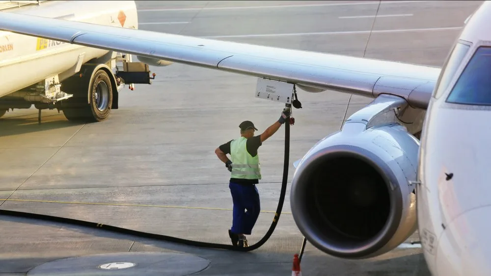 Un angajat al aeroportului umple un avion cu kerosen.