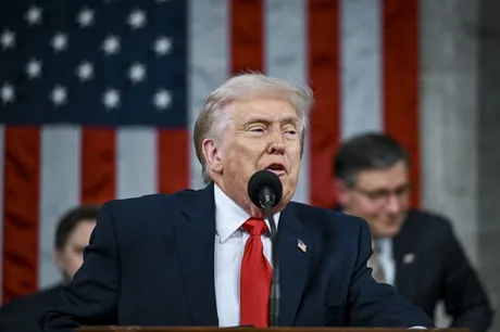 Donald Trump susține un discurs în fața Congresului SUA, cu steagul în fundal.