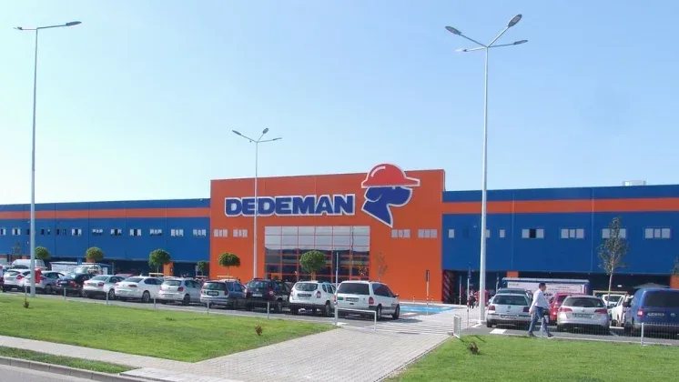 Fațada magazinului Dedeman cu logo-ul distinctiv și culori vibrante.
