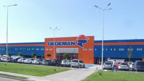 Fațada magazinului Dedeman cu logo-ul distinctiv și culori vibrante.