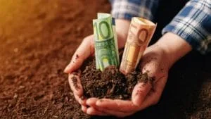 Bani în mâini, simbolizând sprijinul financiar pentru fermieri.