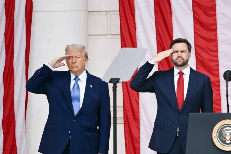 Donald Trump și JD Vance salutând în fața unui fundal cu steaguri americane.