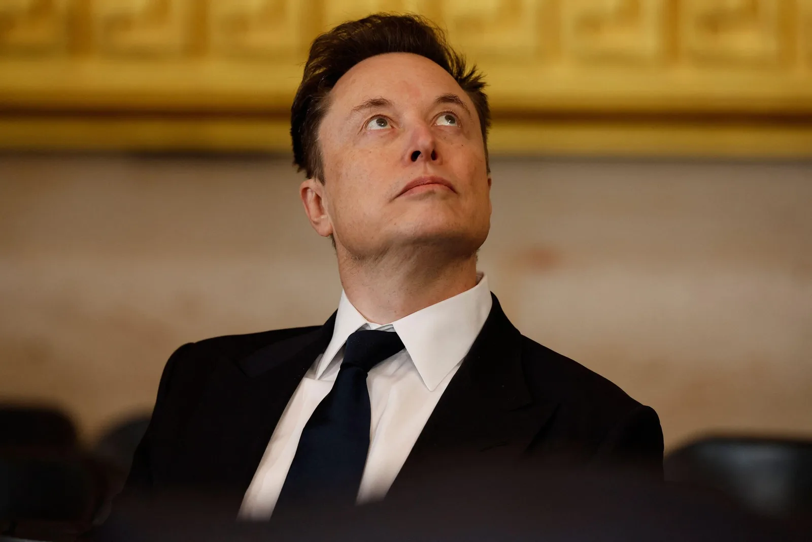 Elon Musk ascultând cu atenție în timpul unei prezentări importante.