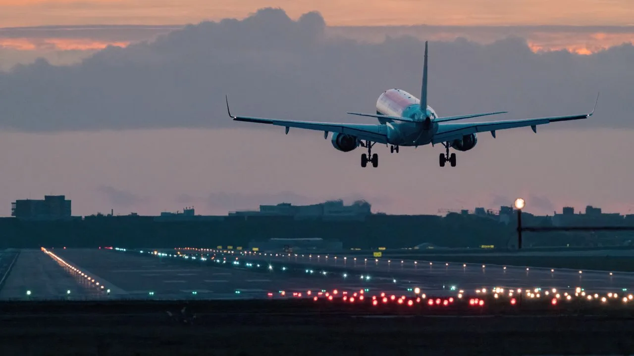 Avion de pasageri aterizând pe un aeroport la apus.