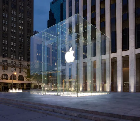 Magazin Apple iluminat noaptea, cu arhitectură modernă din sticlă.