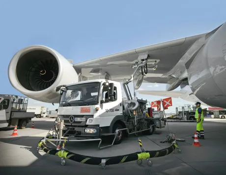 Aprovizionarea cu kerosen la un aeroport european, având un avion în fundal.