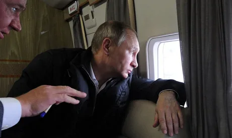Vladimir Putin privind pe fereastră, însoțit de un consilier.
