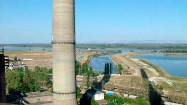 Peisaj industrial cu o termocentrală și un râu în fundal, evidențiind natura și activitatea economică.