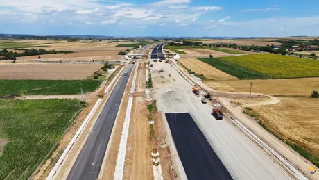 Lucrări la autostrada A3, lotul Biharia–Chiribiș, peisaj rural în fundal.