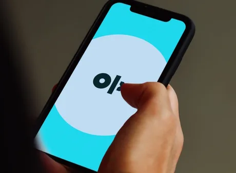 Utilizator navigând pe aplicația OLX pe telefonul mobil.