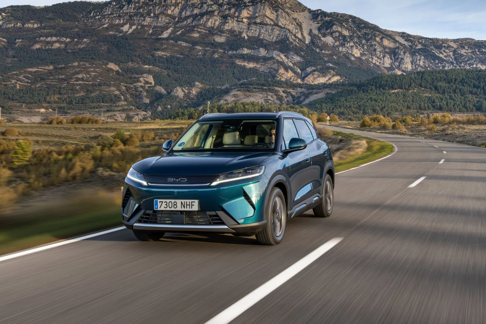 Un SUV electric BYD pe drum, cu peisaj montan în fundal.