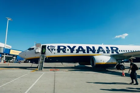Avion Ryanair pregătit pentru îmbarcare pe o pistă însorită.