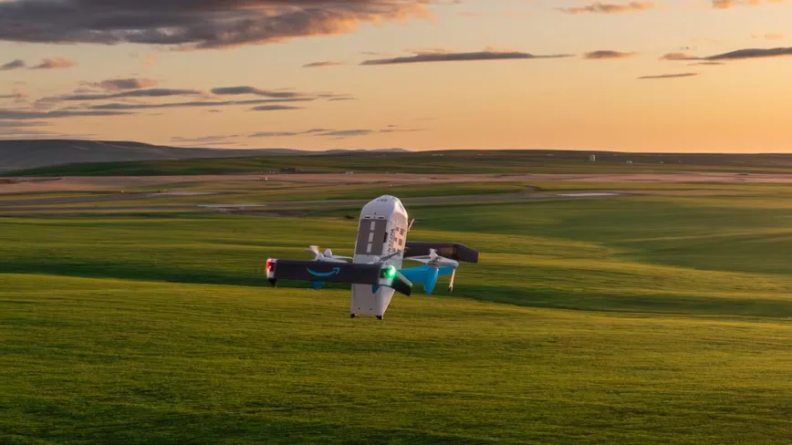 Dronă Amazon în zbor pe un câmp verde la apus.