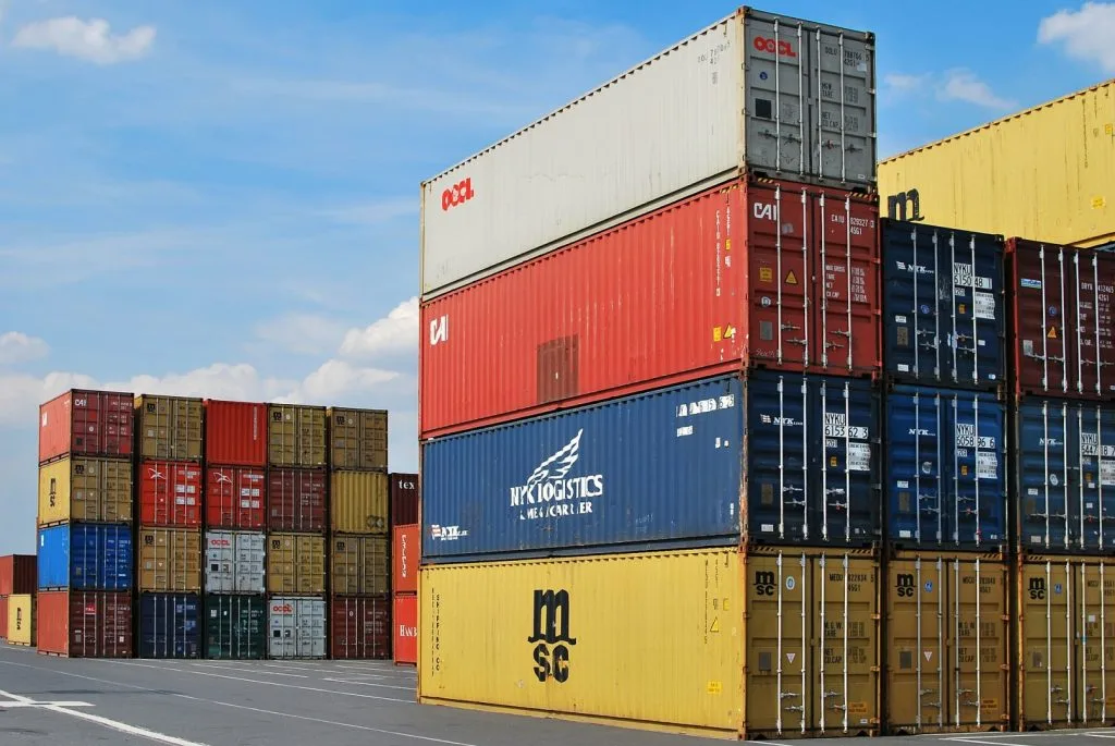 Containere colorate stivuite într-un port, simbolizând comerțul internațional.