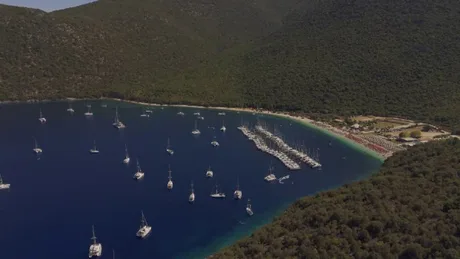 Vedere aeriană a golfului Antisamos cu ambarcațiuni aliniate pe apă.