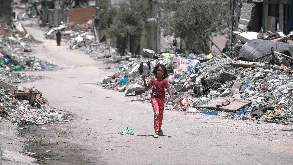 Fată care merge pe o stradă plină de moloz în Gaza