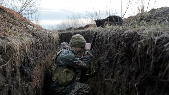 Soldat ucrainean în tranșee, observând atent împrejurimile în timpul conflictului.