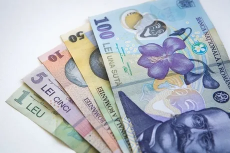Bancnote românești de diferite valori pe o suprafață albă.