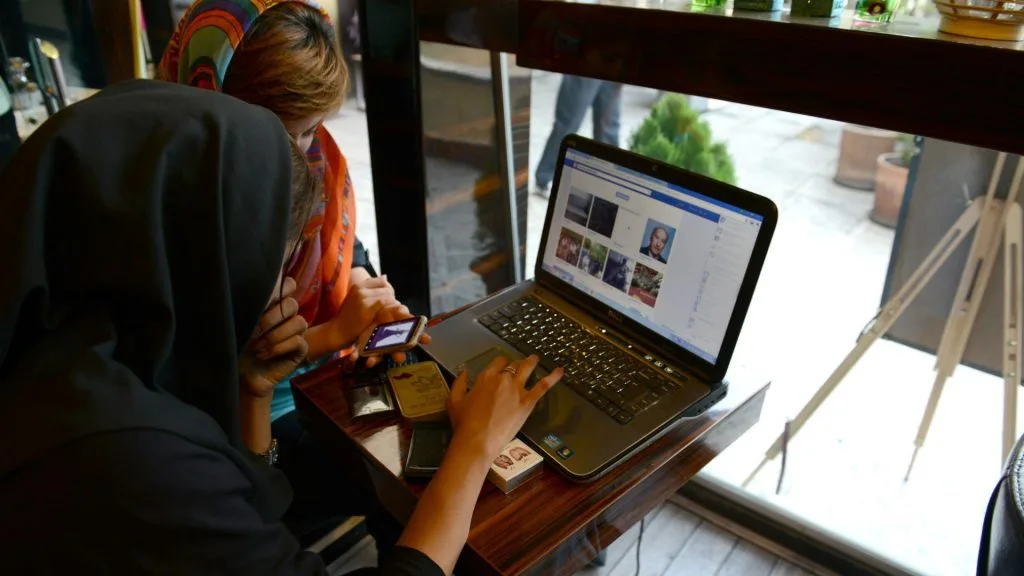Două persoane folosesc internetul într-un local din Teheran.
