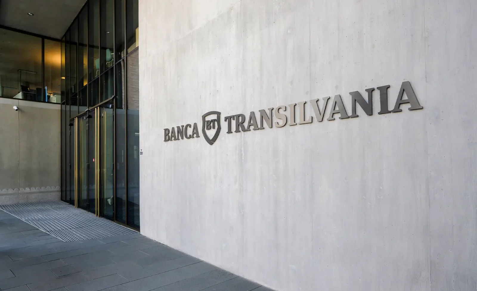 Logo-ul Băncii Transilvania pe un perete modern al clădirii.