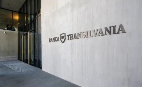 Logo-ul Băncii Transilvania pe un perete modern al clădirii.