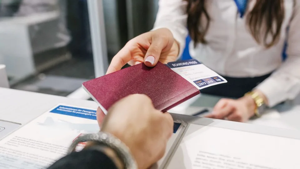 Persoană predând un pașaport la un ghișeu de check-in.