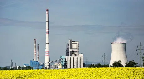 Peisaj industrial cu centrale electrice și câmp de flori galbene.