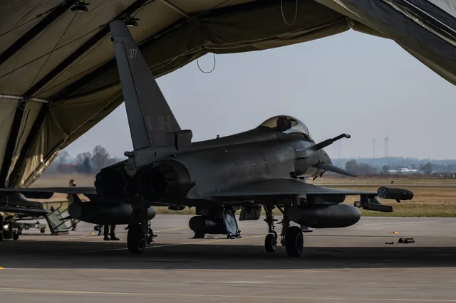 Avion militar pregătit pentru misiune într-un hangar vast.