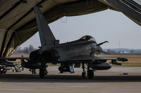 Avion militar pregătit pentru misiune într-un hangar vast.