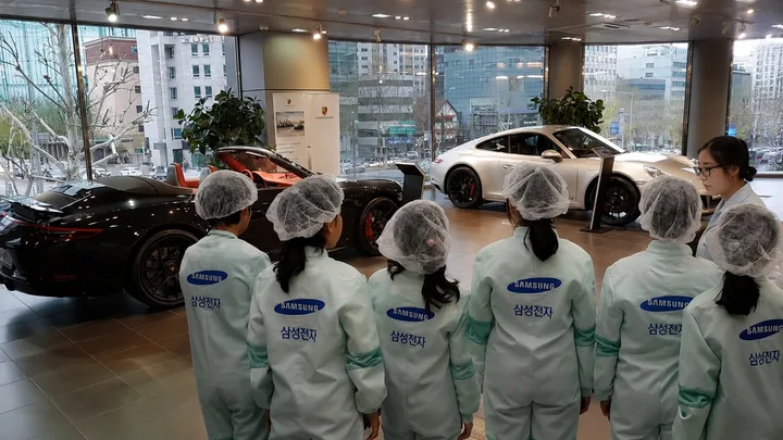 Angajați Samsung admirând mașini de lux într-un showroom Porsche.