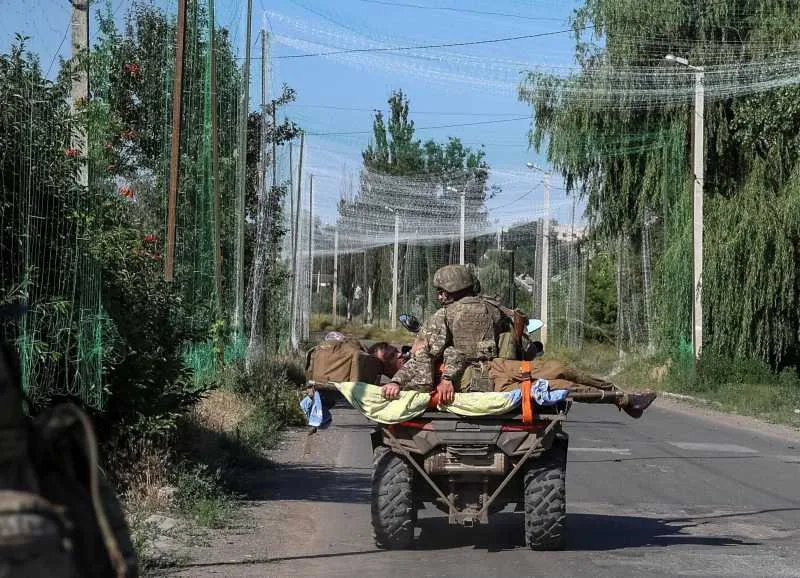 Soldați transportând răniți pe o motocicletă în zona de conflict.