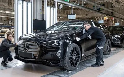 Lucrători pregătesc un automobil electric Mercedes-Benz în fabrică.