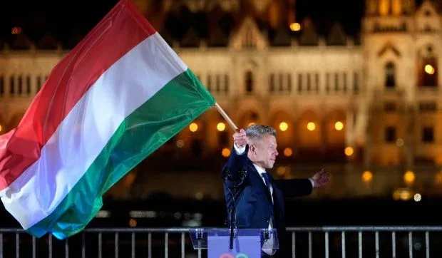 Péter Magyar sărbătorește victoria alegerilor cu steagul Ungariei în fundal.