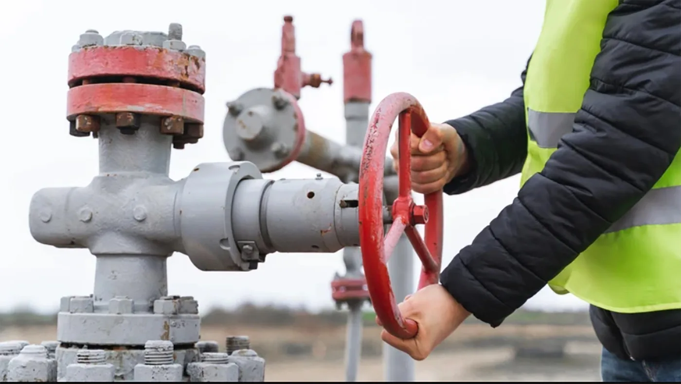 Valvă de gaz reglată de un lucrător în echipament de protecție.