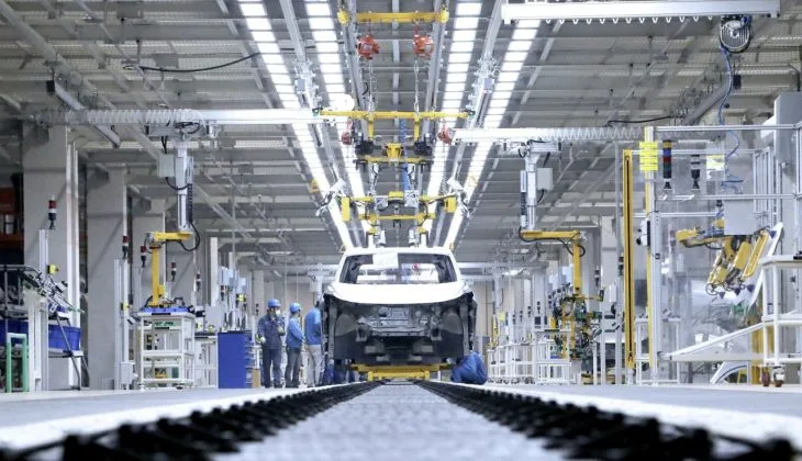 O fabrică de automobile în proces de asamblare, cu muncitori și echipamente moderne.