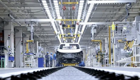O fabrică de automobile în proces de asamblare, cu muncitori și echipamente moderne.