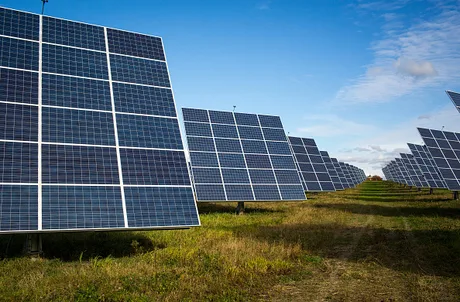 Panouri fotovoltaice amplasate pe un câmp, sub un cer senin.