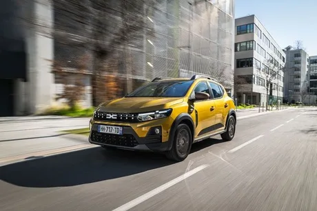 Dacia Sandero circulând pe o stradă urbană modernă.