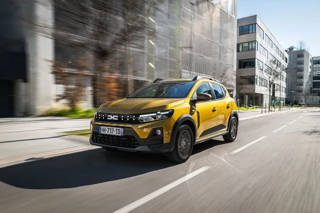 Dacia Sandero circulând pe o stradă urbană modernă.