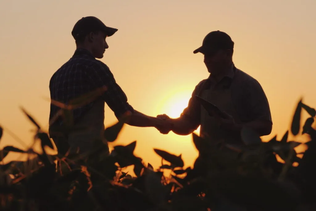 Colaborare între fermieri la apus, simbolizând sprijinul pentru dezvoltarea agriculturii.