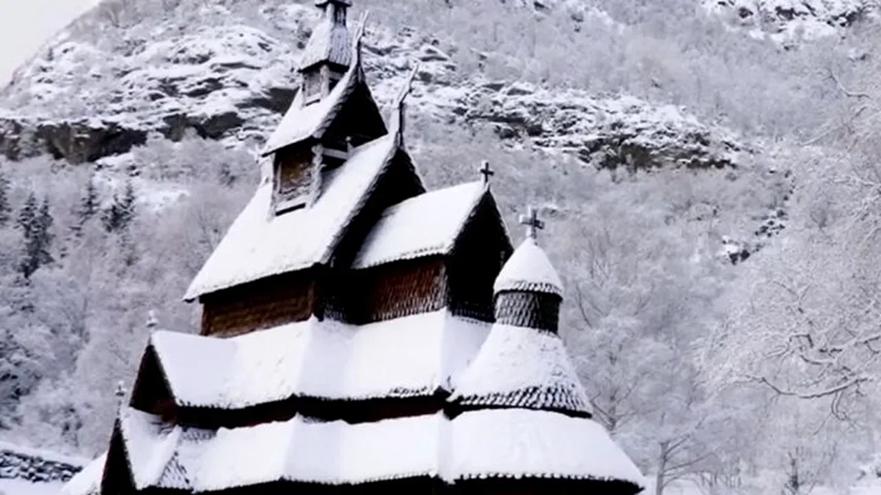 Cabana veche scandinavă acoperită cu zăpadă, în peisaj de iarnă montan.